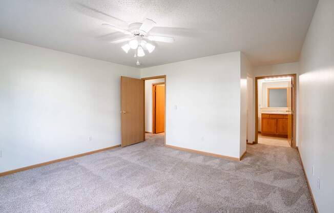A room with a carpeted floor and a ceiling fan. Fargo, ND Stonebridge Apartments