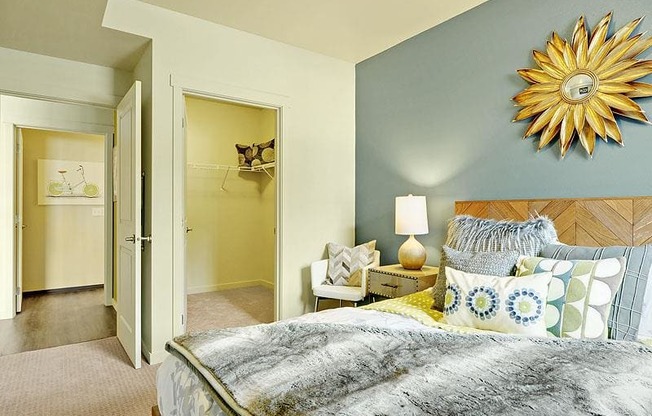 A bedroom with a bed, nightstand, and a wall hanging sunflower. at Kirkland Crossing Apartments, Washington, 98033