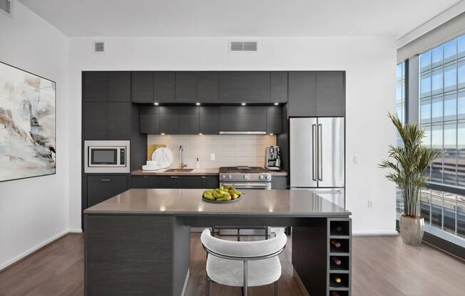 a kitchen with black cabinetry and a island with a bowl of fruit