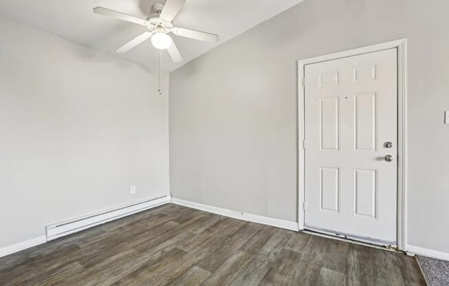 A room with a white door and a ceiling fan.