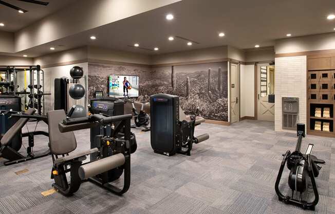 a spacious fitness room with cardio equipment and a large mural of a battlefield