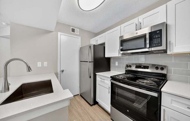 A kitchen with a stove, sink, and refrigerator.