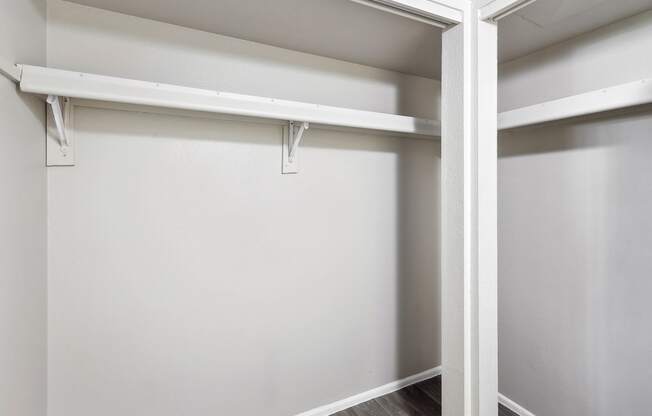 an empty closet in a home with white walls and wood floors