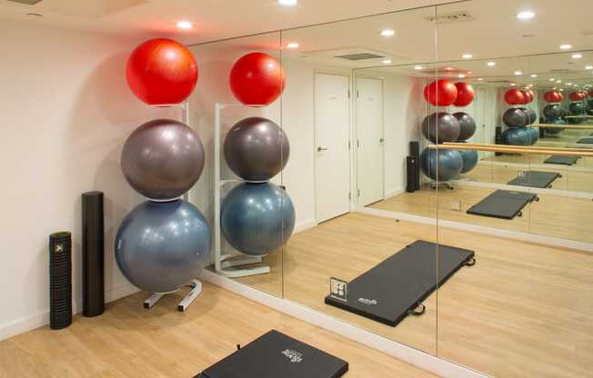 Apartment fitness center with a wall of mirrors, exercise balls, and a stretching mat. at Midvale Court, Los Angeles, CA, 90024