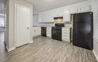 a kitchen with white cabinets and a black refrigerator