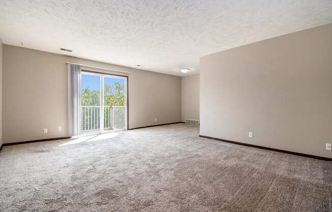 Omaha, NE Maple Ridge Apartments. A living room with a sliding glass door leading to a balcony