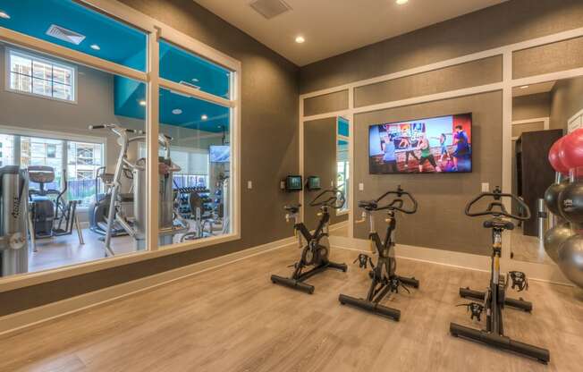 the gym with stationary bikes and a tv