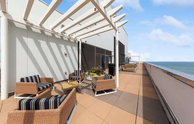 a terrace with wicker chairs and a coffee table with a view of the ocean