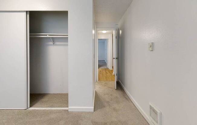 A white closet with a white door is open to a hallway.