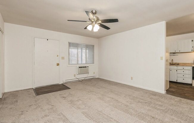 an empty living room with a ceiling fan