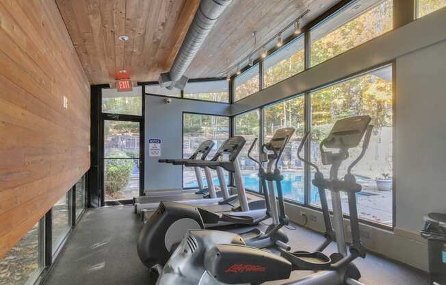 the gym has cardio equipment and views of the pool and trees