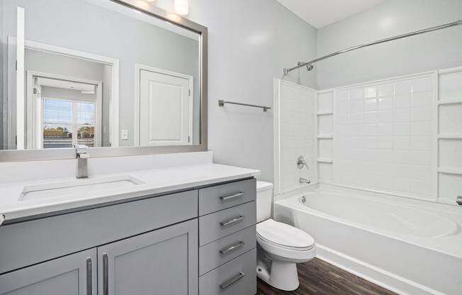 a bathroom with gray cabinets and a white bathtub
