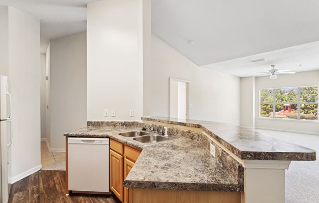 an empty kitchen with granite counter tops and a sink