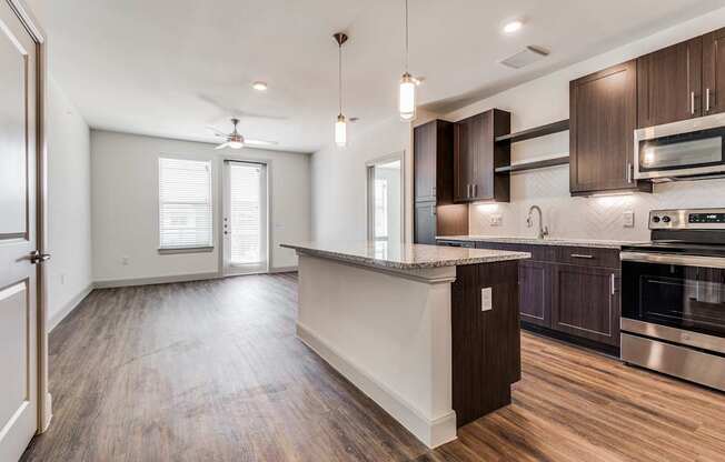 A modern kitchen with dark wood cabinets and stainless steel appliances.