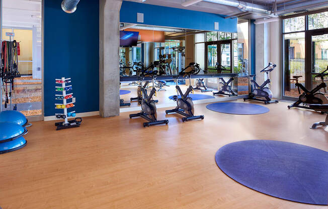 a gym with treadmills and other exercise equipment in a large room with windows