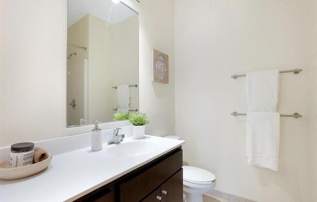 A bathroom with a white counter top and a white toilet.