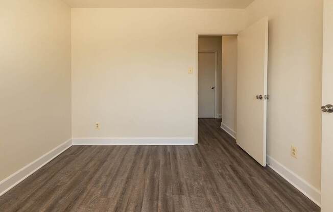 A room with wooden flooring and a doorway leading to another room.