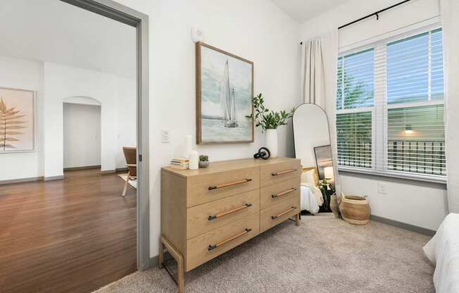 A room with a wooden floor and a dresser with a painting on the wall.