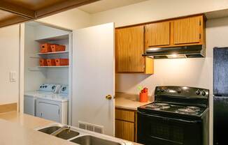 A kitchen with a black stove and wooden cabinets.