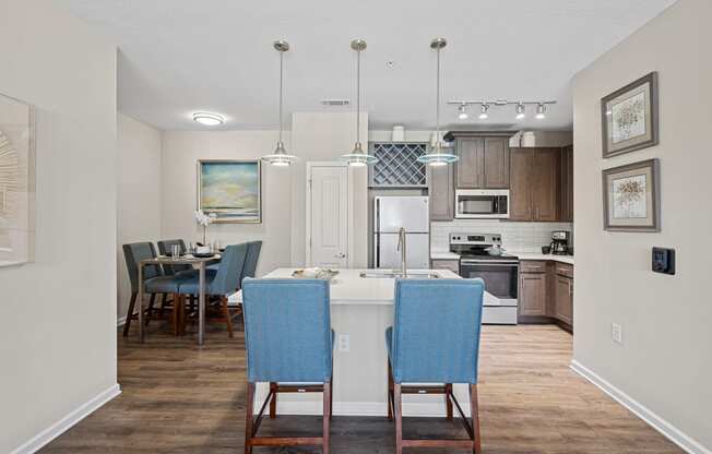 an open kitchen and dining area with blue chairs and a white counter top