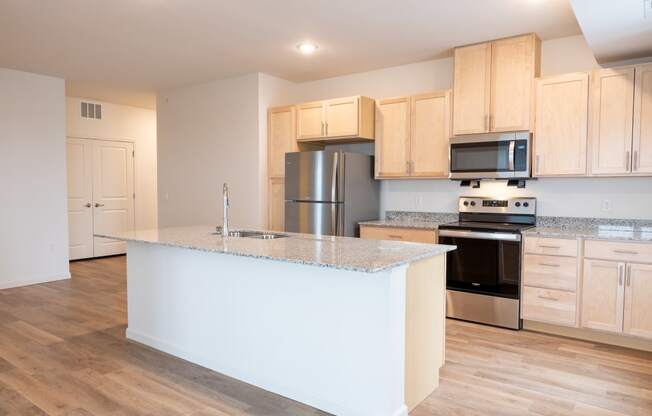 a kitchen with a large island and a stainless steel refrigerator