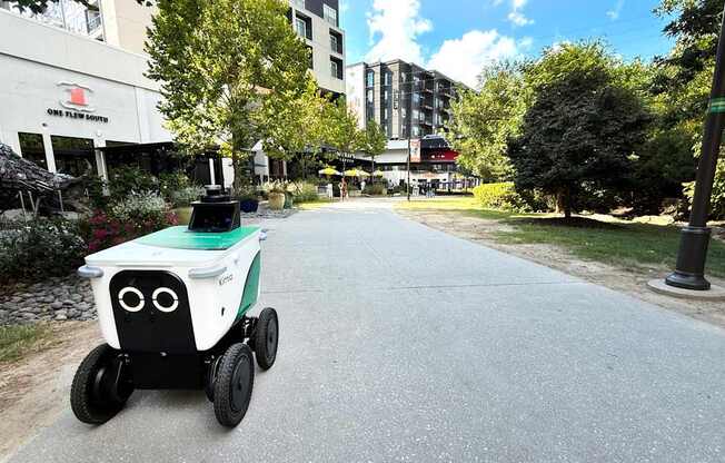A small white and black robotic vehicle is driving down a city street. at West Inman Lofts, Atlanta