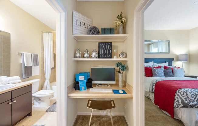 a bedroom with a desk with a computer on it and a bed