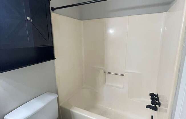 A white toilet sits next to a bathtub in a small bathroom.