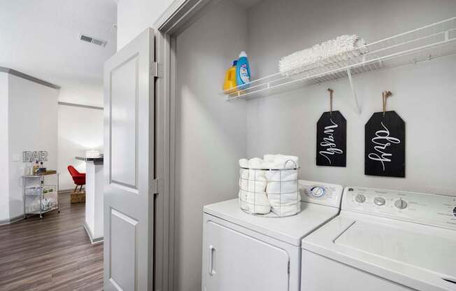 A laundry room with a washer and dryer and a broom.