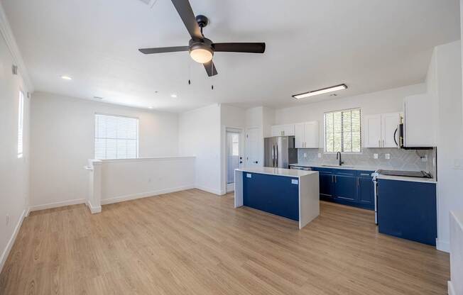 A spacious kitchen with blue cabinets and a ceiling fan.