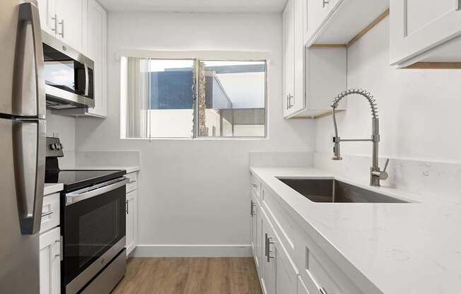 A modern kitchen with white cabinets and stainless steel appliances.