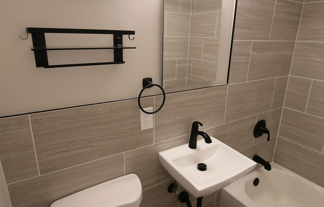 Modern bathroom featuring elegant tiling, sleek fixtures, and a stylish bathtub for a luxurious experience.