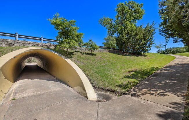 a tunnel on the side of a hill with grass and trees at Lakeline East Apartments, Cedar Park, TX