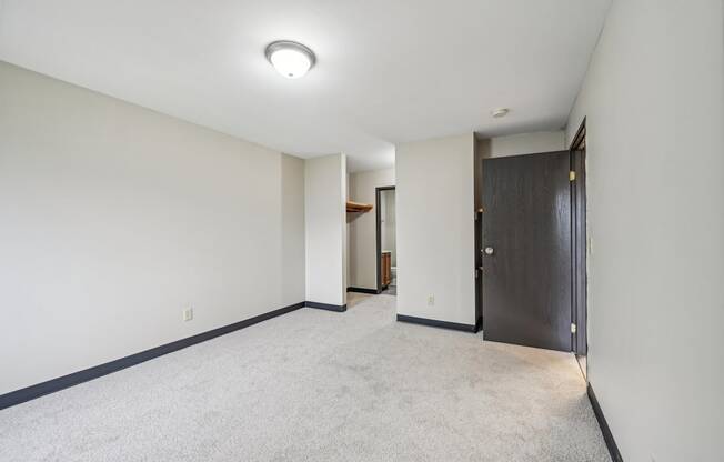 a living room with white walls and a door to a hallway