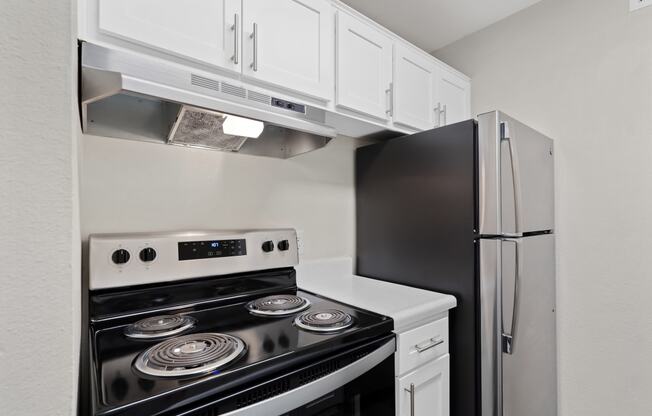 a kitchen with white cabinets and black appliances and a refrigerator