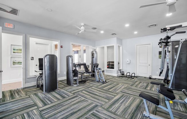 A gym with a variety of equipment including a treadmill, weights, and a stationary bike.