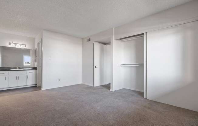 an empty living room with white cabinets and a kitchen