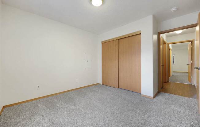 A room with a grey carpet and a wooden door.