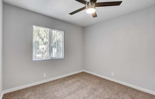 an empty room with a window and a ceiling fan