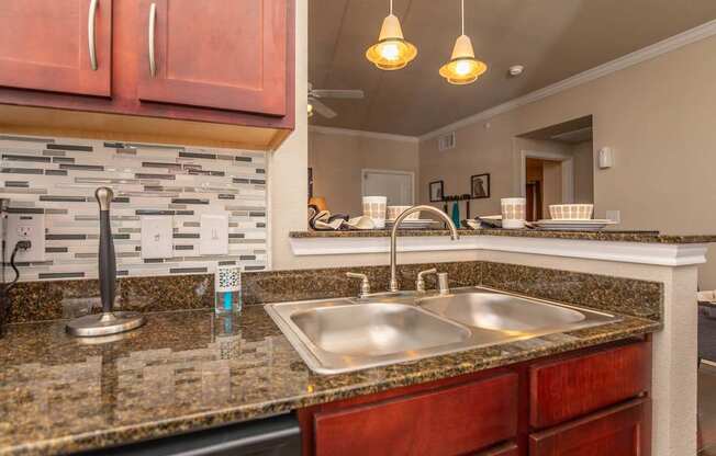 A kitchen with a granite countertop and a stone backsplash.