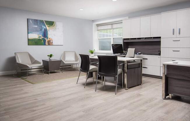 A modern office space with a desk, chairs, and a painting on the wall.