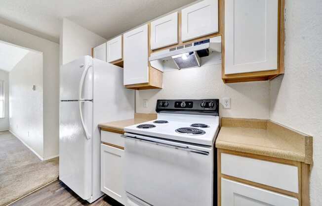 a kitchen with white appliances and white cabinets and a refrigerator