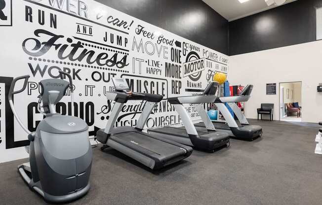 a gym with weights and a wall mural of gym equipment