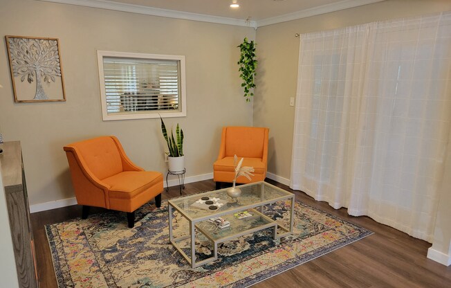 a living room with two orange chairs and a glass coffee table