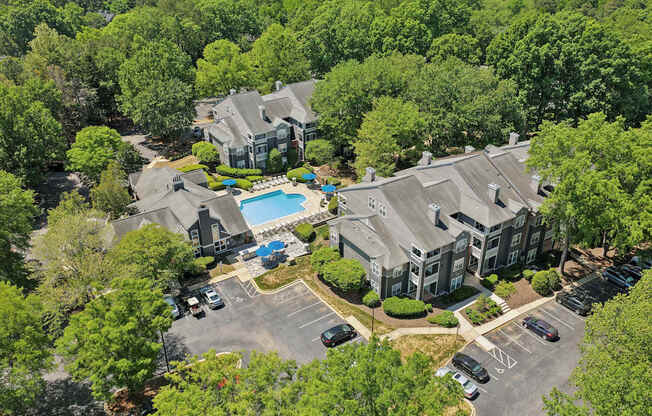 A bird's eye view of a residential area with houses, a swimming pool, and a parking lot.