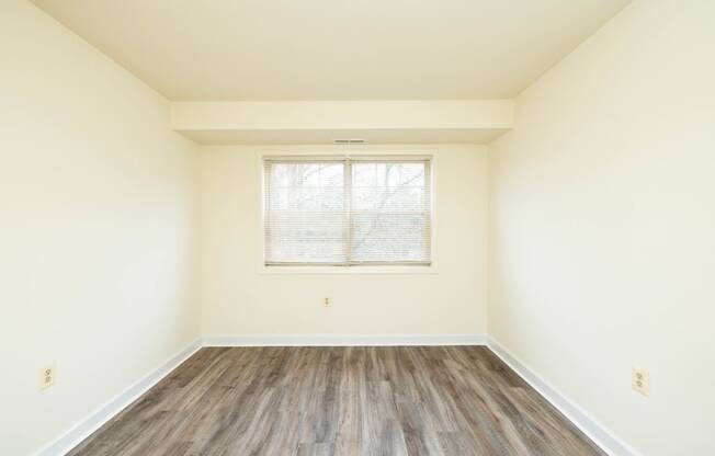 a bedroom with hardwood floors and white walls