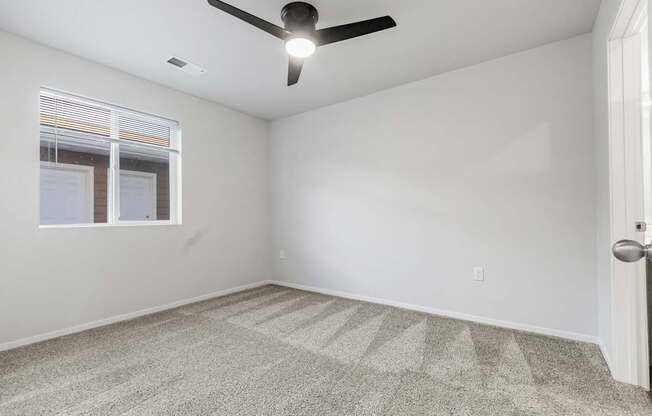 A room with a ceiling fan and carpeted floor.