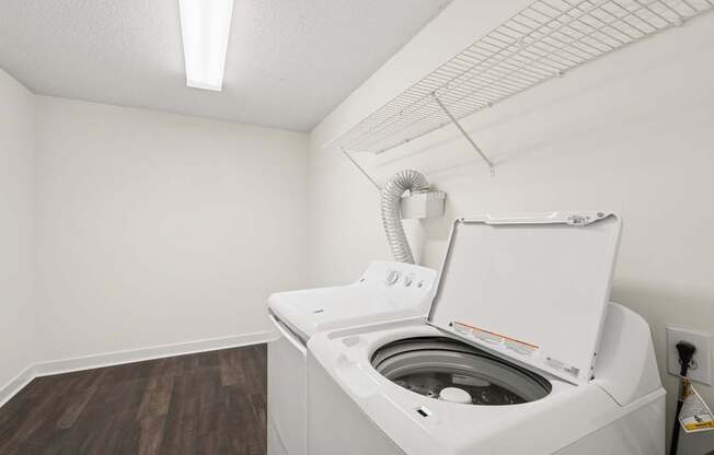 A white washing machine in a small room with wood flooring.