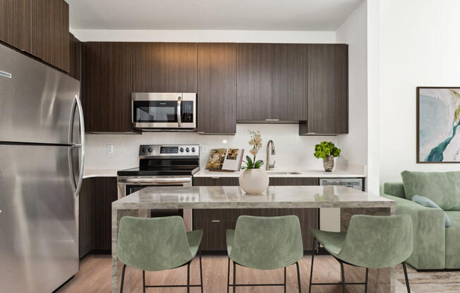 a kitchen with a large island with a marble countertop and four green chairs at The Box, Richmond, 23224