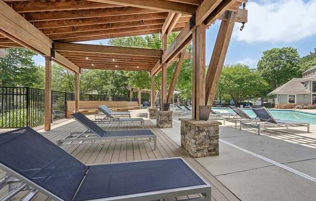 A wooden deck with sun loungers and a pergola.